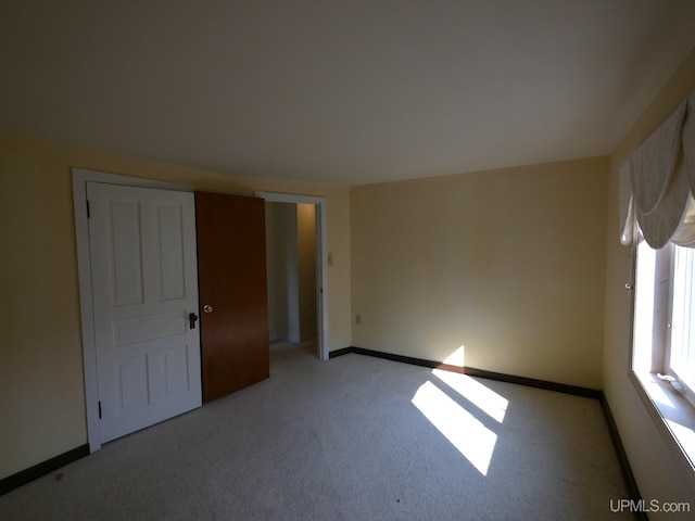empty room with baseboards and light colored carpet