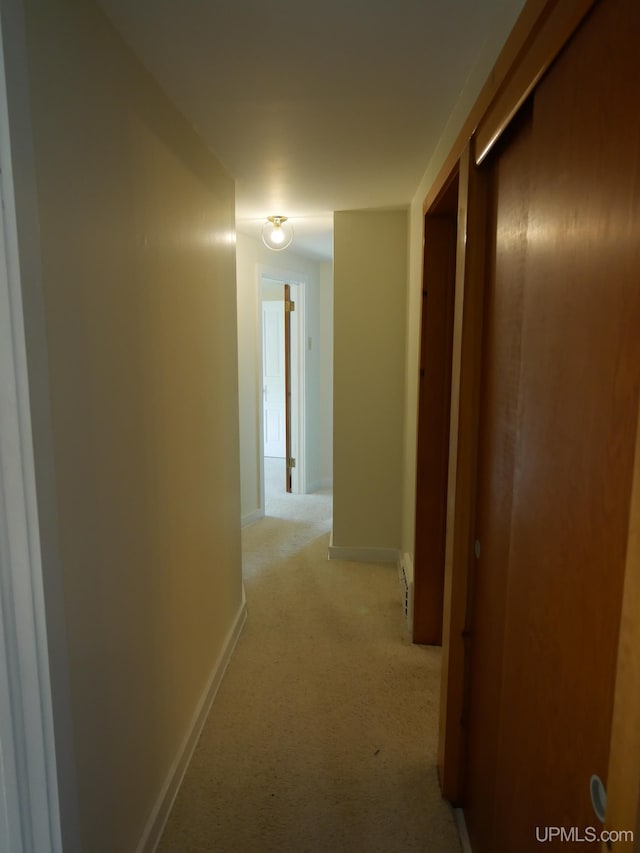 corridor featuring light carpet and baseboards