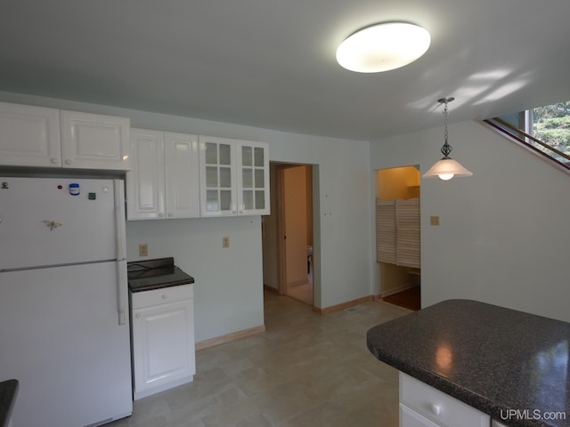 kitchen with freestanding refrigerator, dark countertops, white cabinetry, and glass insert cabinets