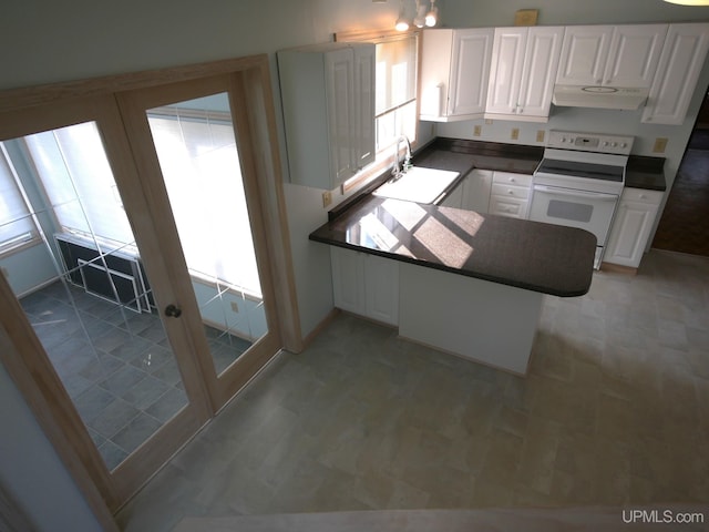 kitchen with a peninsula, a sink, dark countertops, under cabinet range hood, and white range with electric stovetop