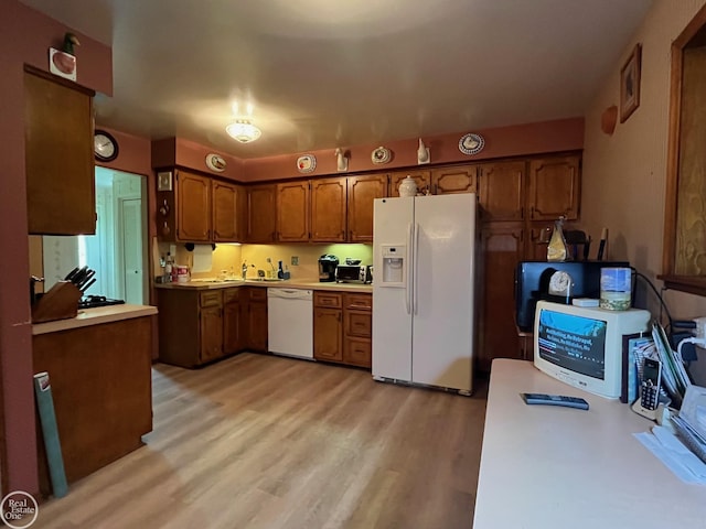 kitchen featuring light countertops, light wood-type flooring, brown cabinets, and white appliances