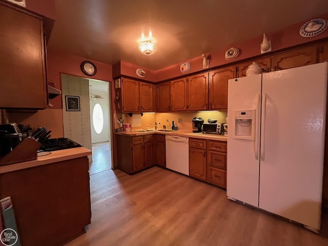 kitchen with brown cabinetry, white appliances, light countertops, and light wood-style floors