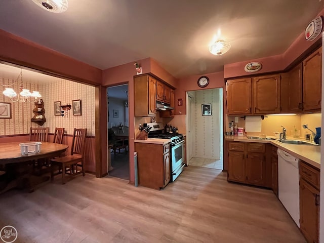 kitchen featuring stainless steel gas stove, a notable chandelier, under cabinet range hood, light countertops, and white dishwasher