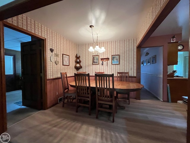 dining space with a notable chandelier, visible vents, wainscoting, and wallpapered walls