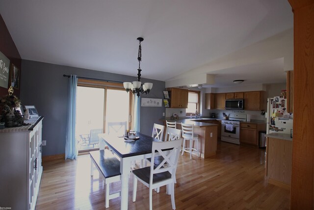 dining space with light wood-type flooring, a chandelier, and lofted ceiling