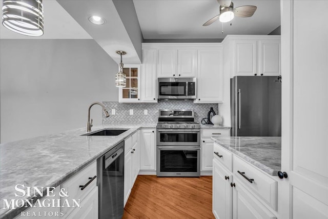 kitchen featuring stainless steel appliances, white cabinets, light wood-type flooring, and a sink