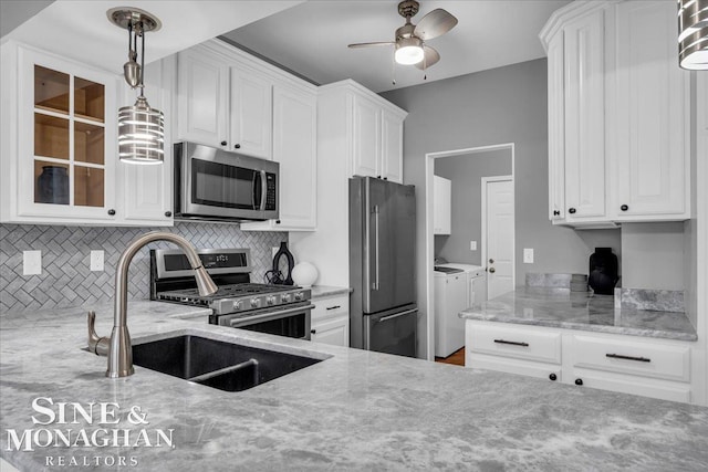 kitchen with a sink, washer and dryer, ceiling fan, backsplash, and appliances with stainless steel finishes