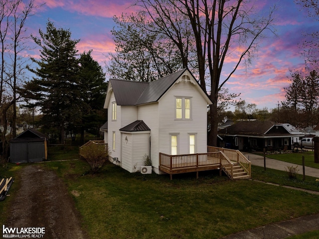 traditional-style home featuring metal roof, a deck, a front yard, and a storage unit
