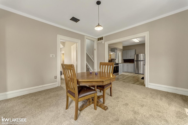 dining room featuring ornamental molding, light carpet, baseboards, and visible vents