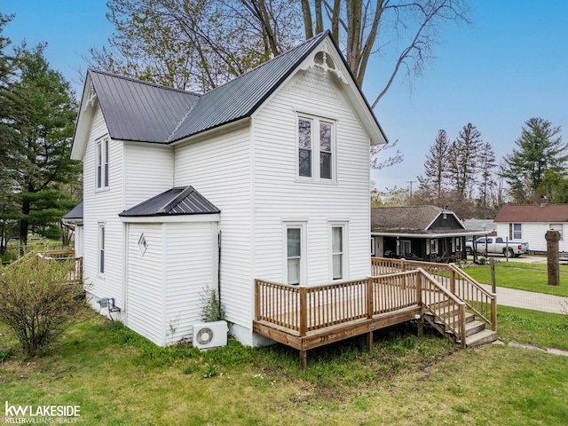 rear view of house with a yard, a deck, metal roof, and ac unit