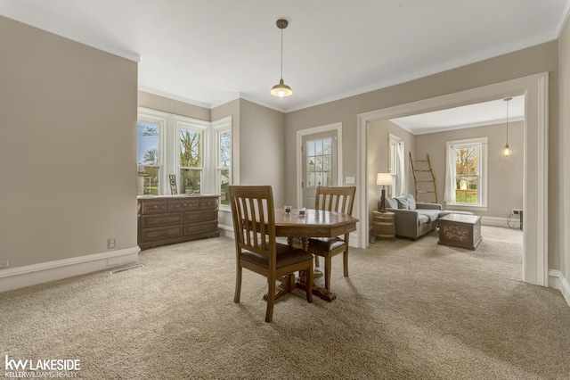 carpeted dining space featuring ornamental molding, plenty of natural light, baseboards, and visible vents