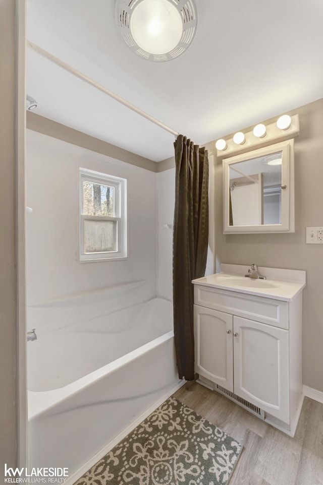 full bath with vanity, baseboards, shower / tub combo, and wood finished floors