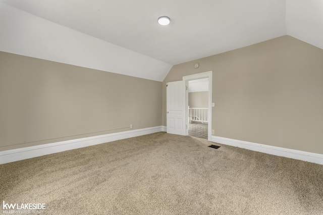 additional living space featuring vaulted ceiling, carpet, baseboards, and visible vents