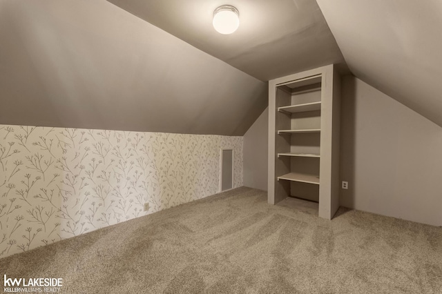 bonus room with lofted ceiling, wallpapered walls, and carpet