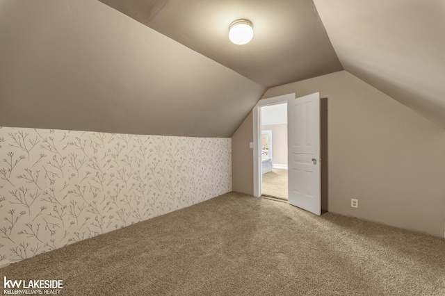 bonus room featuring lofted ceiling, carpet, and wallpapered walls