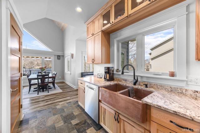 kitchen featuring glass insert cabinets, a sink, light brown cabinets, baseboards, and dishwasher