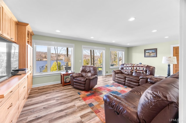 living area with baseboards, a water view, light wood-style flooring, and recessed lighting