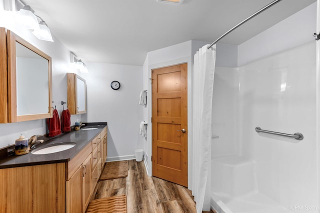 full bath with a sink, double vanity, curtained shower, and wood finished floors