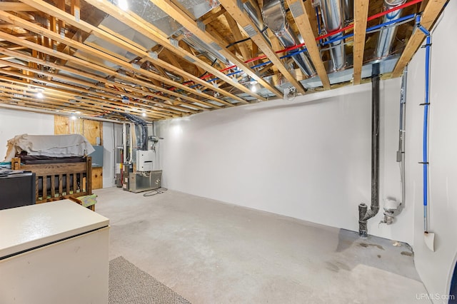 unfinished basement featuring white fridge and heating unit