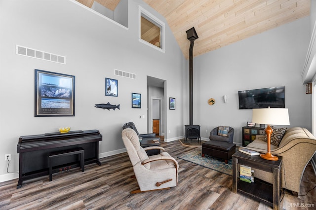 living room featuring a wood stove, visible vents, high vaulted ceiling, and wooden ceiling