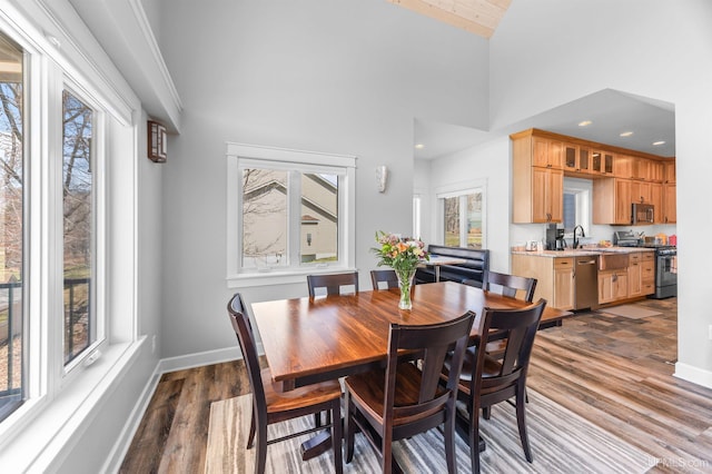 dining area featuring recessed lighting, wood finished floors, baseboards, and high vaulted ceiling