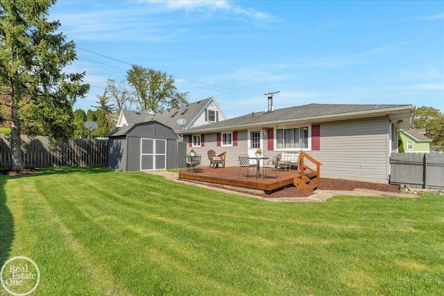 rear view of property with a deck, a shed, an outdoor structure, and a fenced backyard
