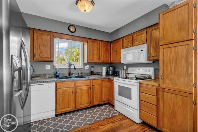 kitchen with brown cabinetry, white appliances, and a sink