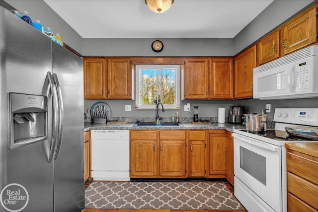 kitchen featuring brown cabinets, white appliances, light countertops, and a sink