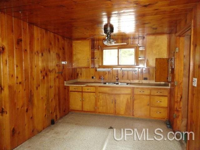 kitchen featuring wooden ceiling, wood walls, a sink, and light countertops