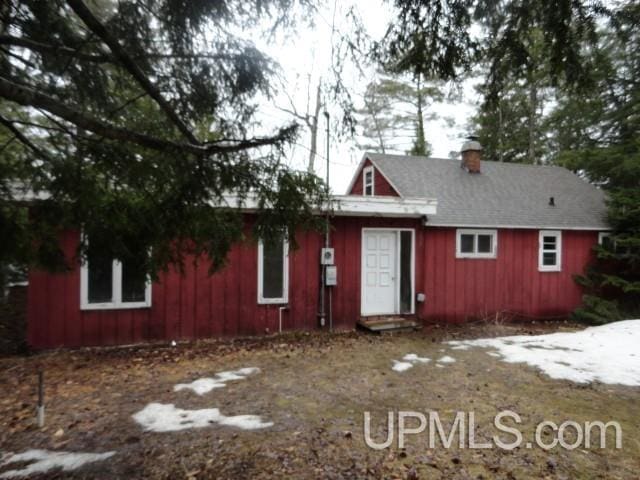 rear view of house with a chimney, entry steps, and board and batten siding