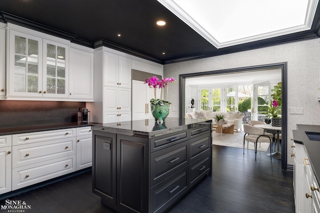 kitchen with dark wood-type flooring, white cabinetry, a center island, glass insert cabinets, and dark cabinets