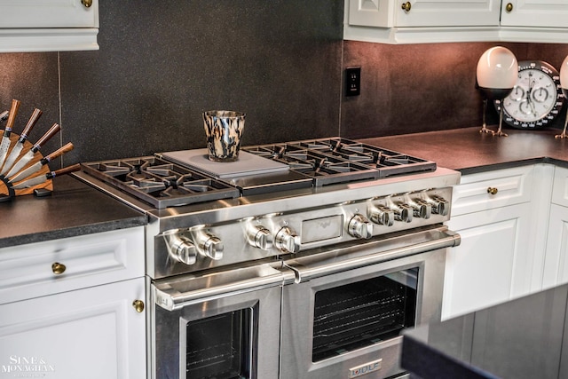 kitchen with backsplash, double oven range, and dark countertops