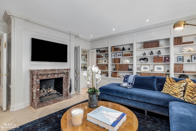 living room with crown molding, a fireplace, and built in shelves