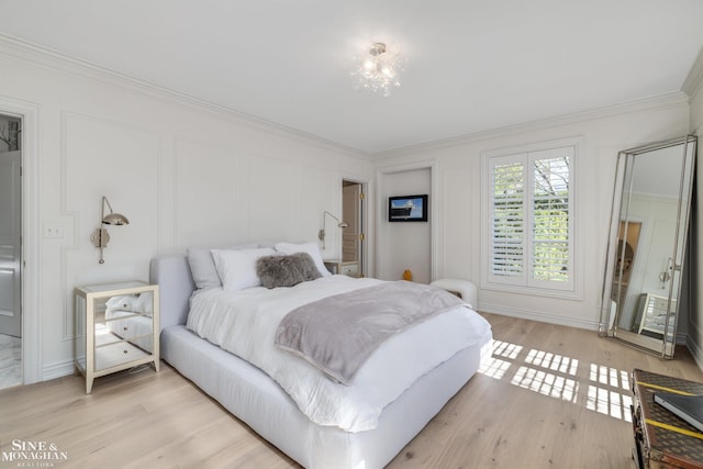 bedroom featuring a decorative wall, light wood-style flooring, and ornamental molding