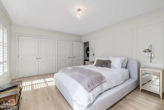 bedroom featuring crown molding, light wood-style flooring, multiple closets, and multiple windows