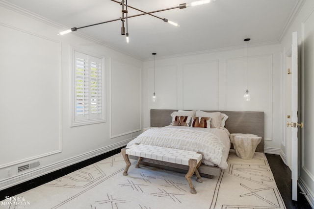 bedroom featuring baseboards, visible vents, a decorative wall, and crown molding