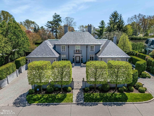 view of front facade featuring a fenced front yard, a gate, a high end roof, and a chimney