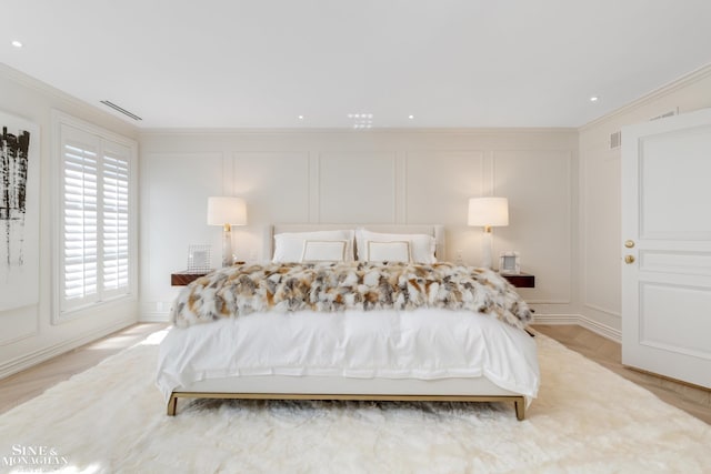 bedroom featuring visible vents, a decorative wall, and ornamental molding