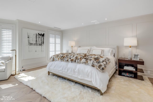 bedroom with crown molding, a decorative wall, and visible vents