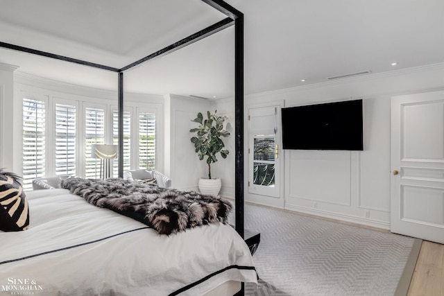 bedroom with visible vents, crown molding, and wood finished floors