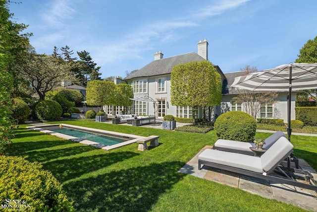 back of property featuring a yard, a chimney, a patio area, and an outdoor living space