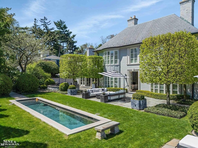 back of house featuring an outdoor living space, a chimney, a lawn, an outdoor pool, and a high end roof