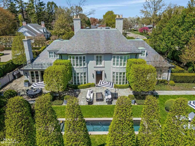 exterior space featuring a patio, a high end roof, and a chimney