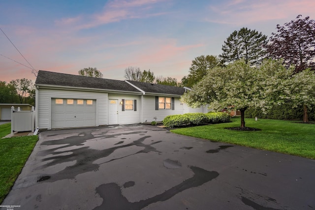 single story home featuring aphalt driveway, an attached garage, and a front yard