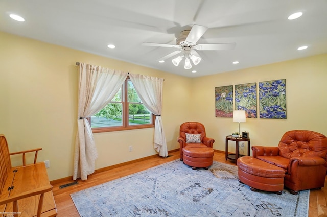 living area with baseboards, a ceiling fan, and wood finished floors