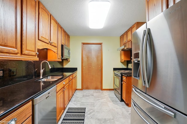kitchen with under cabinet range hood, stainless steel appliances, a sink, and brown cabinets