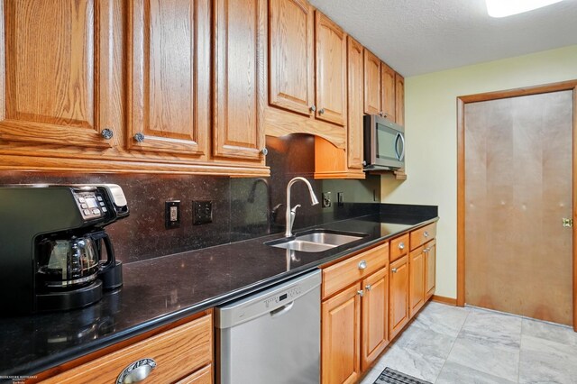 kitchen with dark stone countertops, appliances with stainless steel finishes, decorative backsplash, and a sink