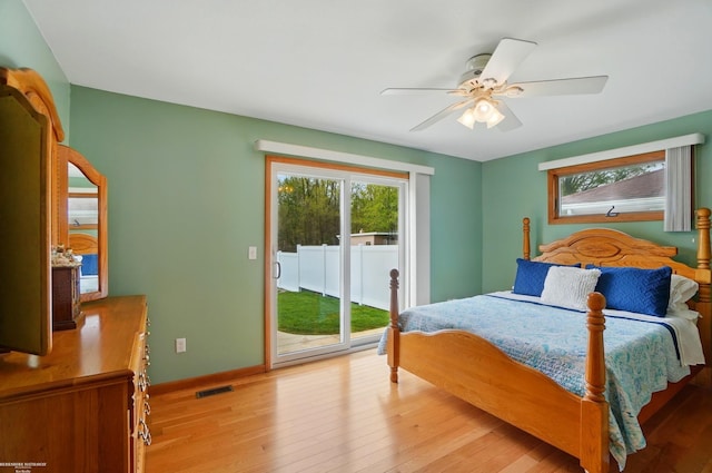 bedroom with multiple windows, wood finished floors, visible vents, and access to exterior