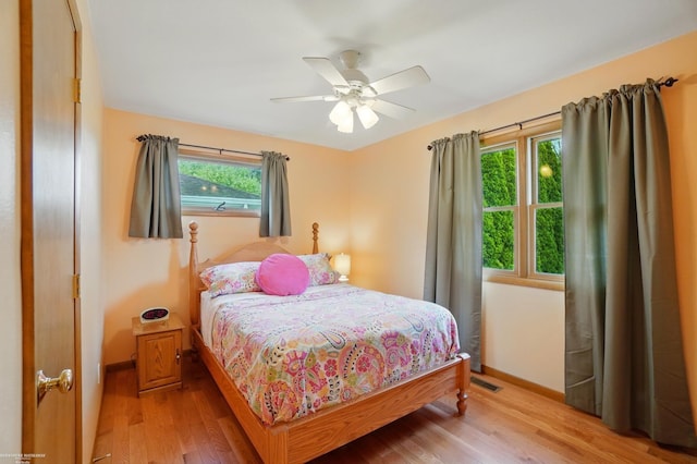 bedroom featuring light wood finished floors, baseboards, a ceiling fan, and visible vents