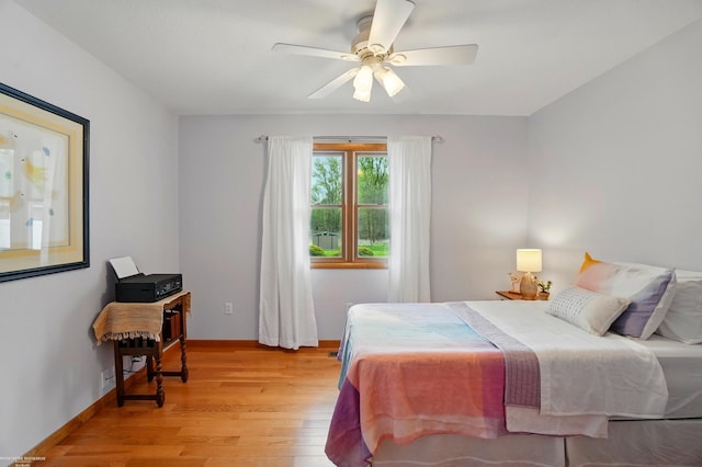 bedroom with a ceiling fan, light wood-style flooring, and baseboards